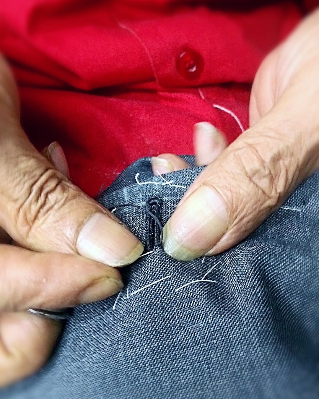 Hands of a late master tailor sewing by hand