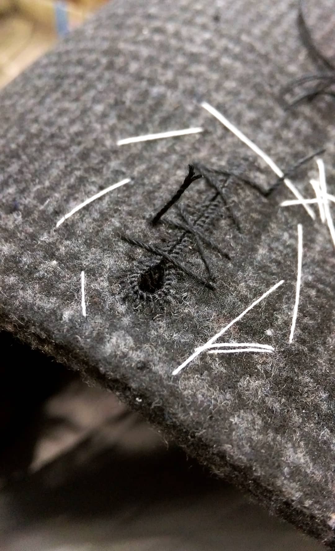 Finished hand-sewn buttonhole on grey cloth